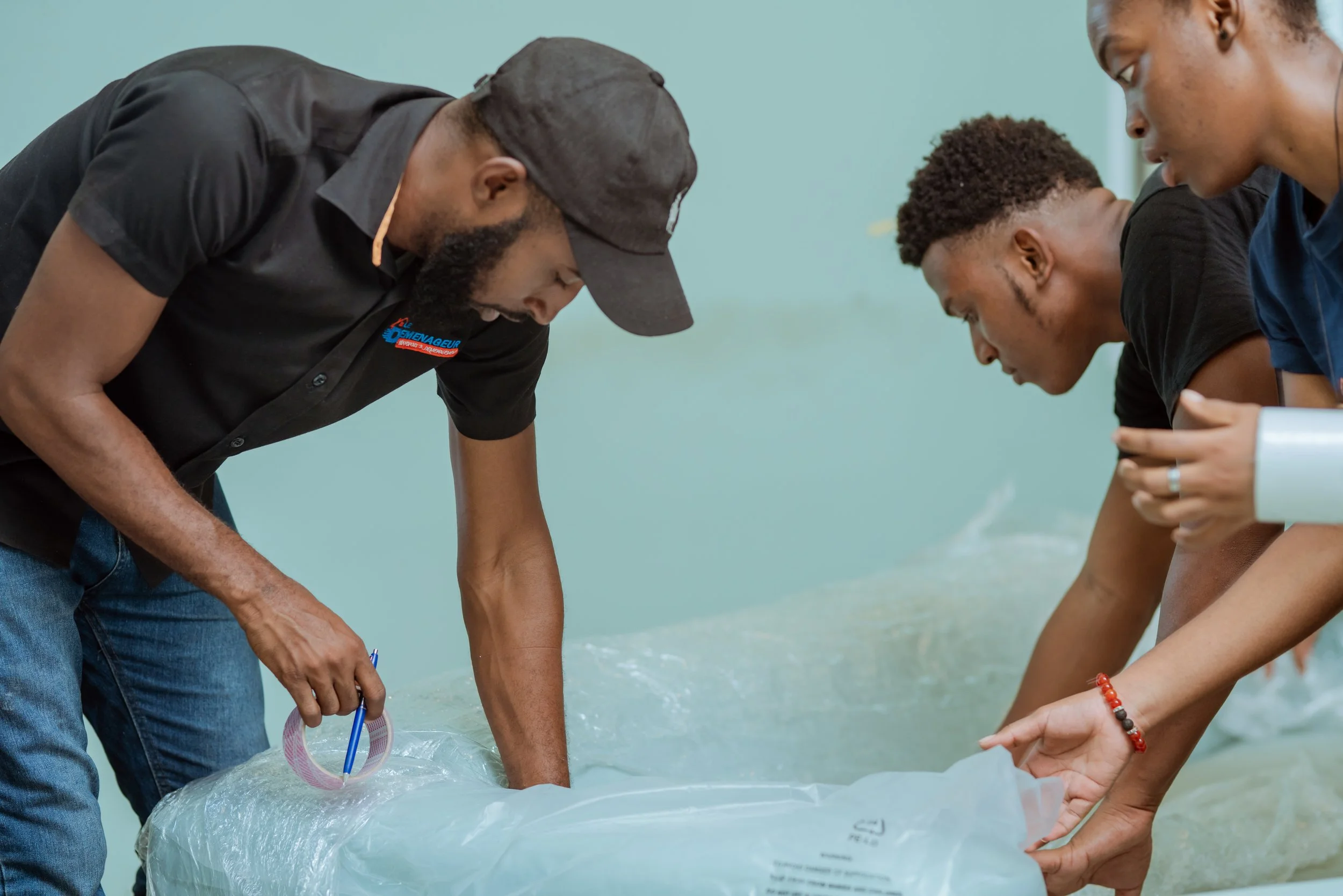 Three individuals working together to handle a large plastic bag or sheet, possibly during an activity or project.