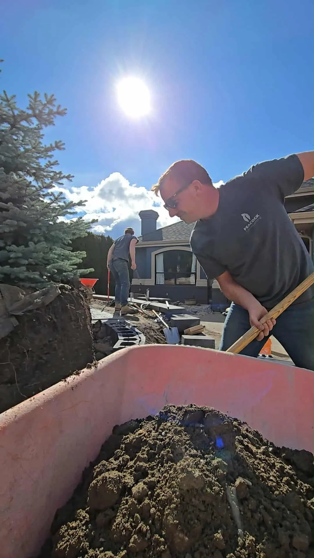 Two of the Peacock Landscaping crew working outdoors on landscaping project under a sunny sky in Vernon.