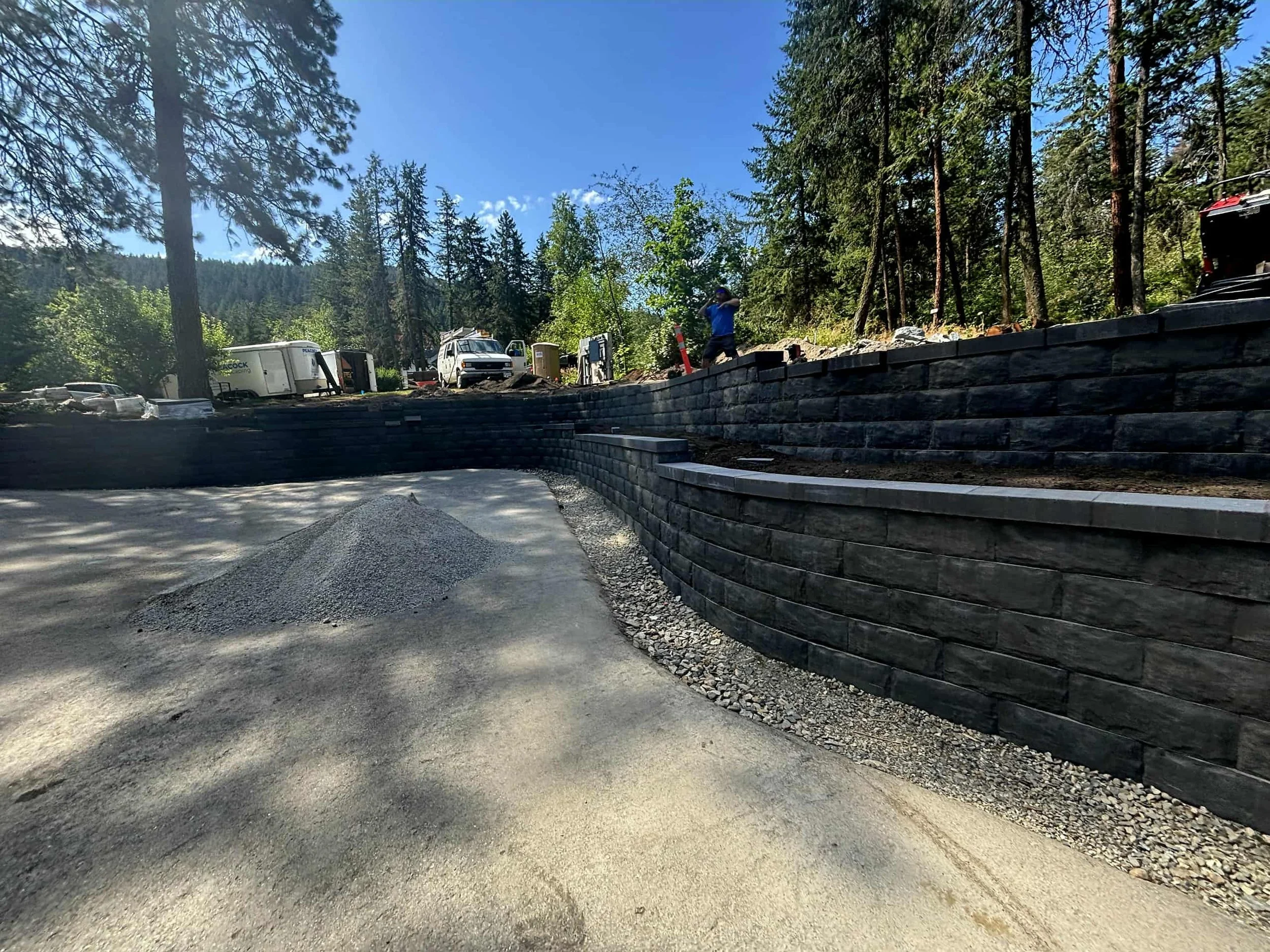 A large, tiered stone retaining wall and gravel driveway by Peacock Landscaping in Vernon.