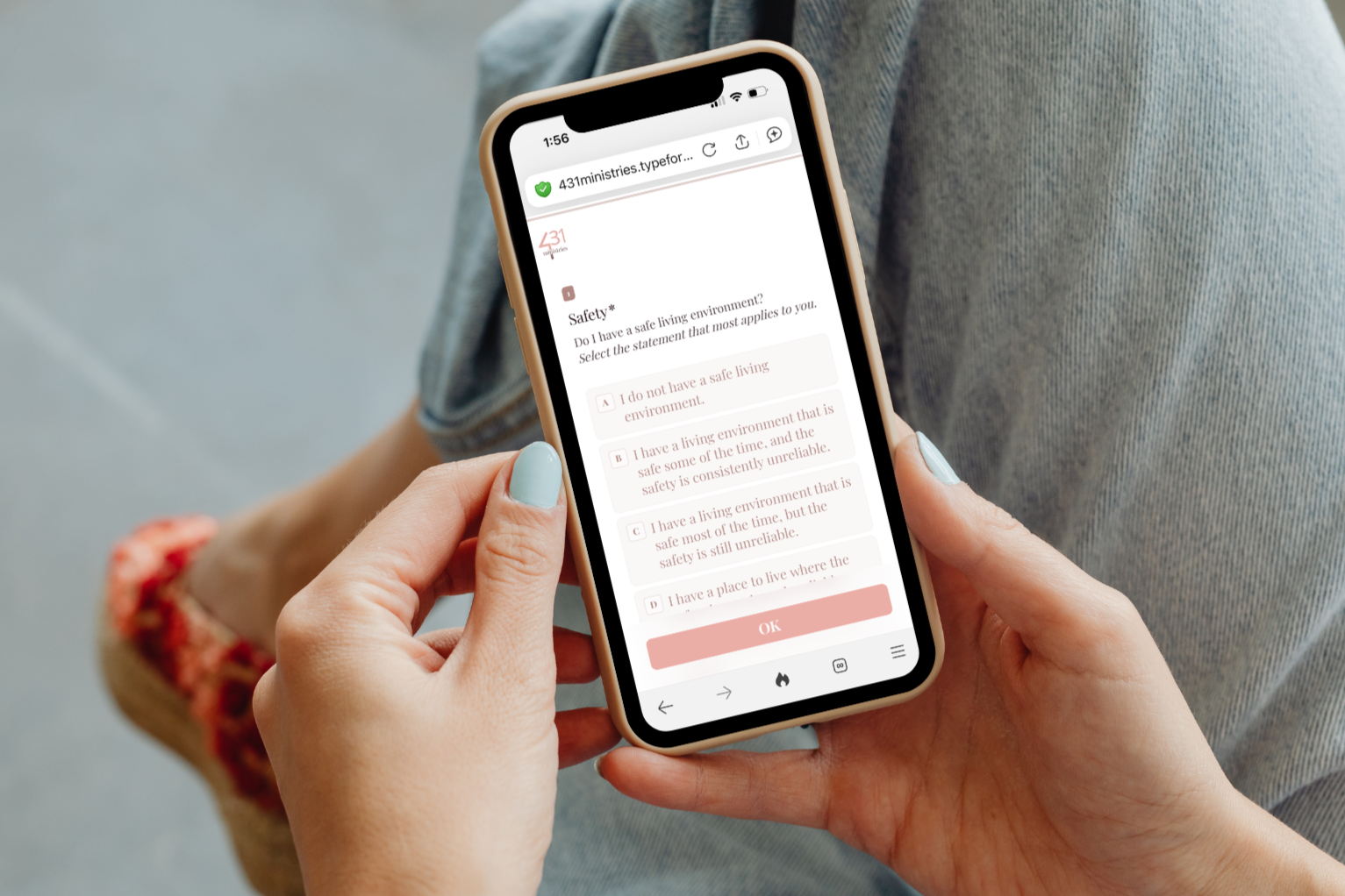 A person typing on a laptop keyboard at a wooden table, wearing a smartwatch and rings on their fingers.