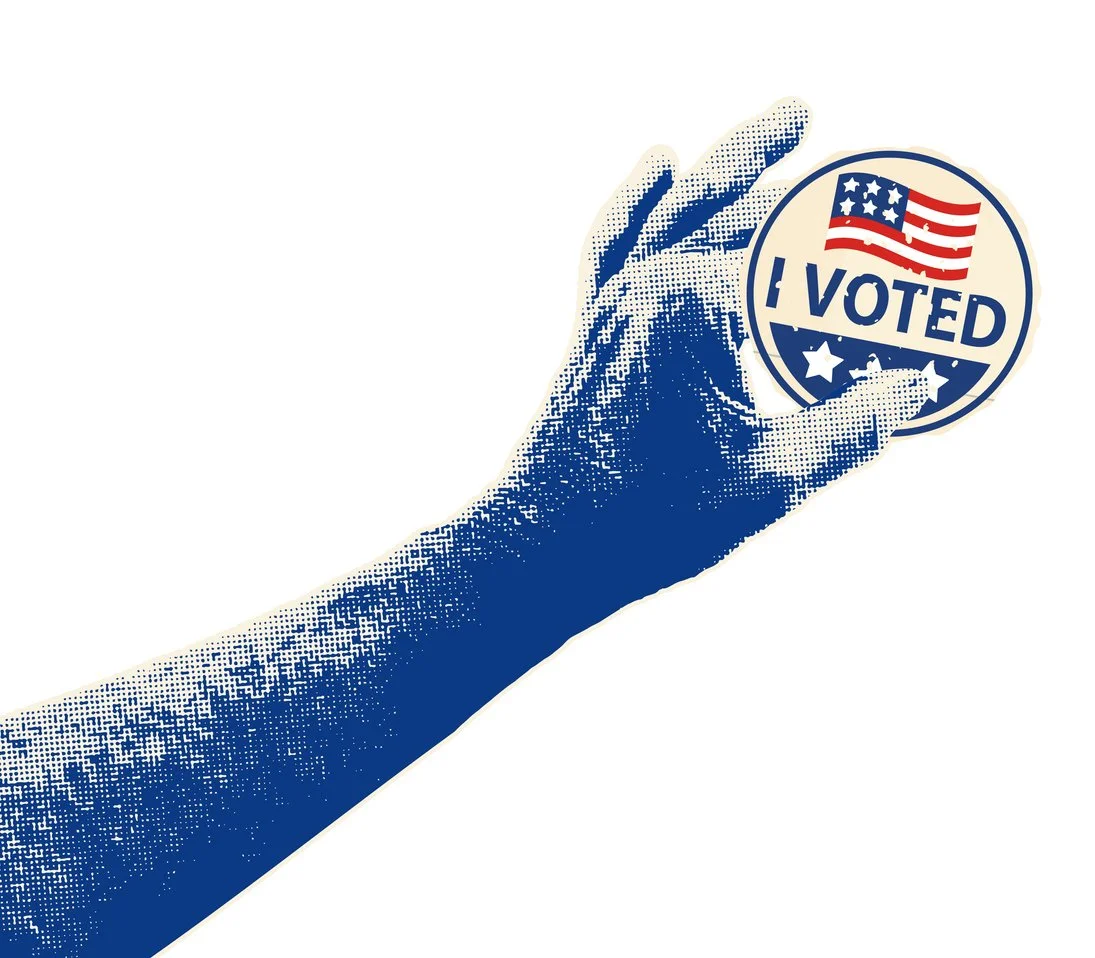 Close-up of a hand holding a circular sticker with an American flag and the text 'I Voted' on it.
