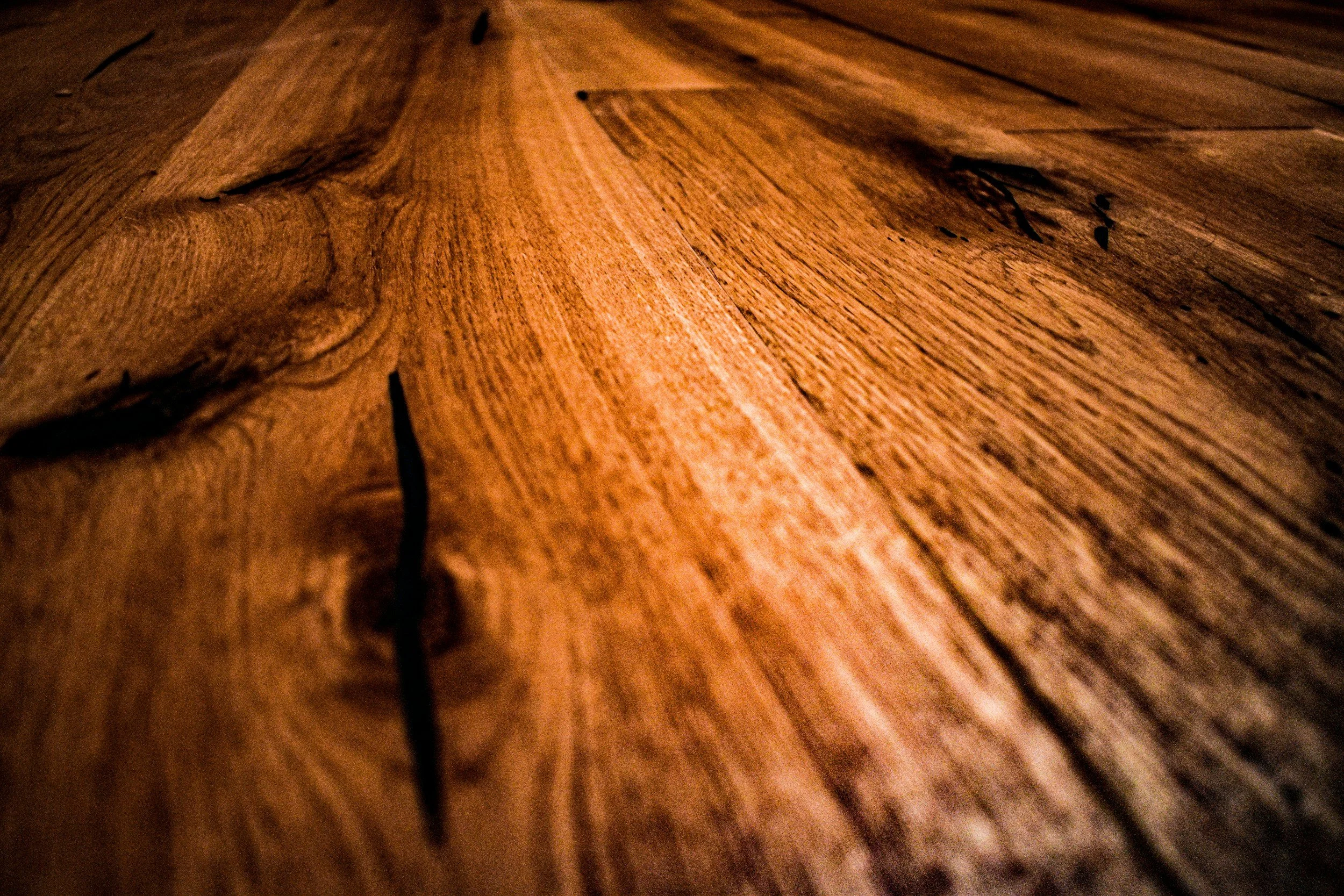 Close-up view of a wooden floor with visible grains and cracks.