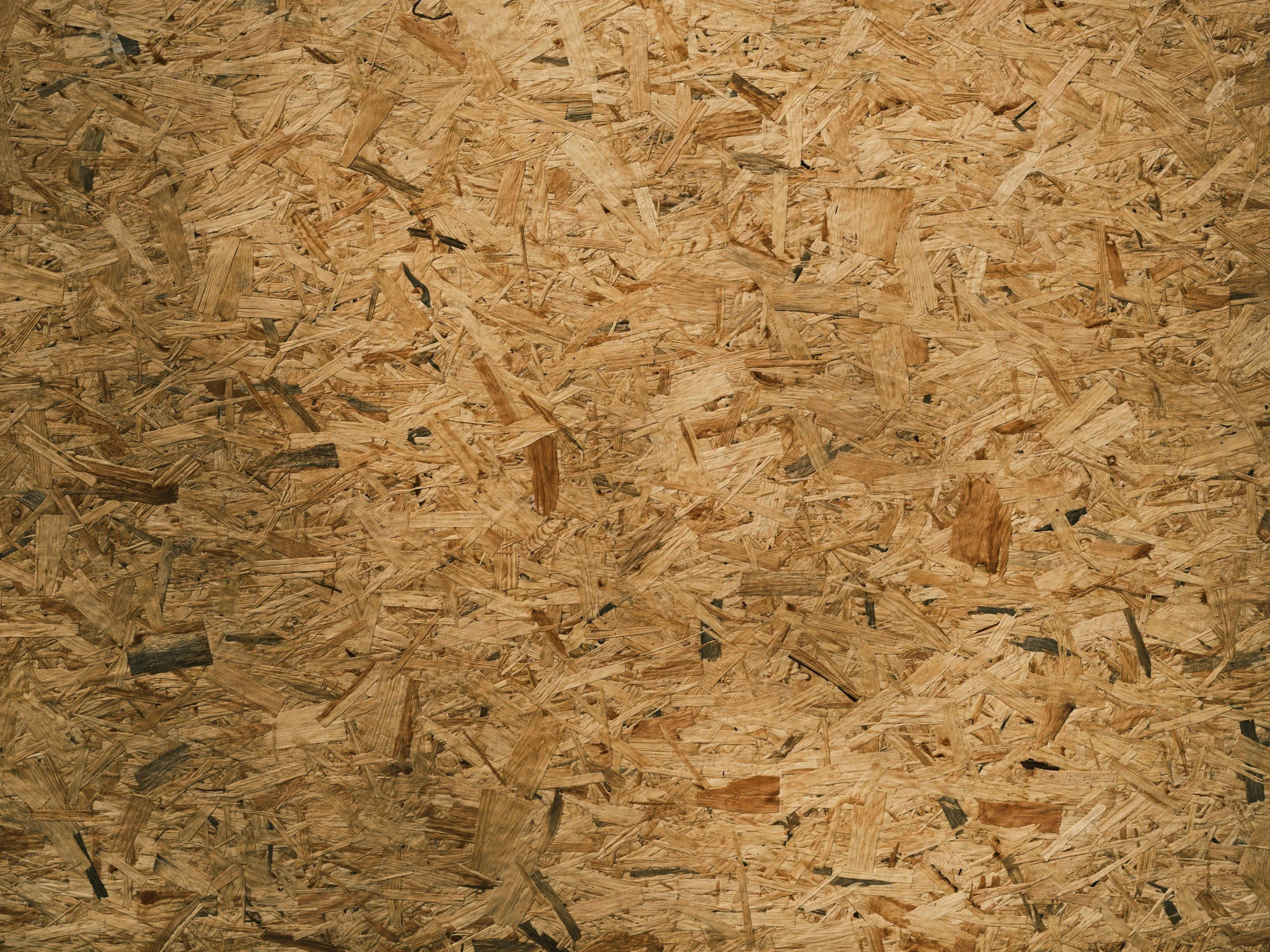 Close-up of a textured wooden surface made of oriented strand board (OSB) with irregular wood chips and fibers.