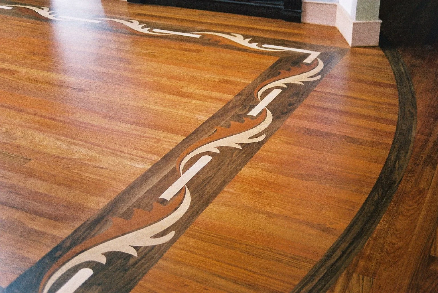 Close-up of a wooden floor with an intricate inlay border design in dark and light wood tones. Beautiful hardwood floors.