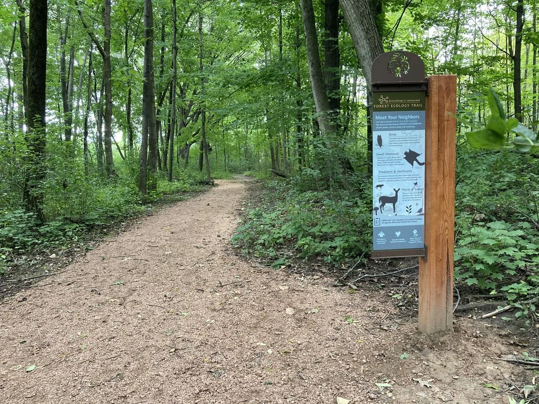 Educational signage along the trail features forest ecology and wildlife themes