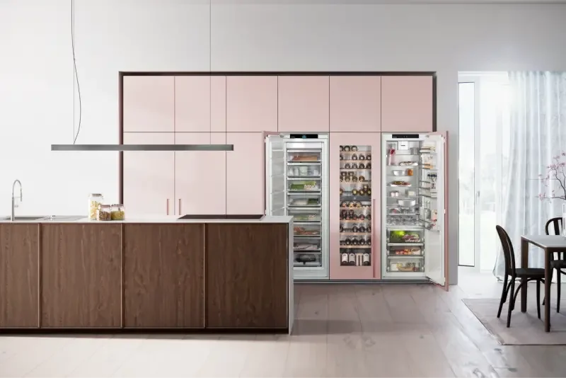 Moderne Küche mit pinken Schränken und offenem Kühlschrank, Kücheninsel mit dunklen Fronten und heller Arbeitsplatte aus Naturstein