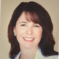 Headshot of a woman with shoulder-length dark hair, smiling, wearing a white top.