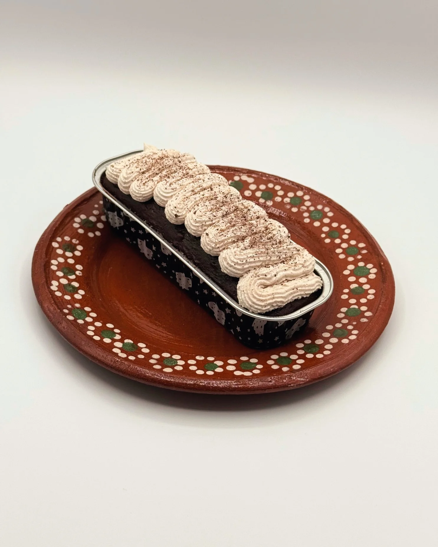 Chocolate dessert with piped whipped topping on a decorative clay plate.