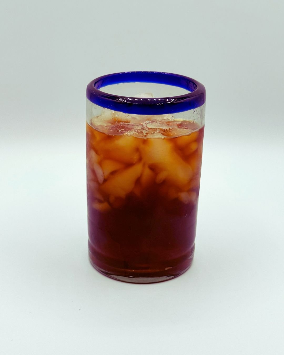 Glass of iced cola with ice cubes, with a purple rim on the top of the glass.