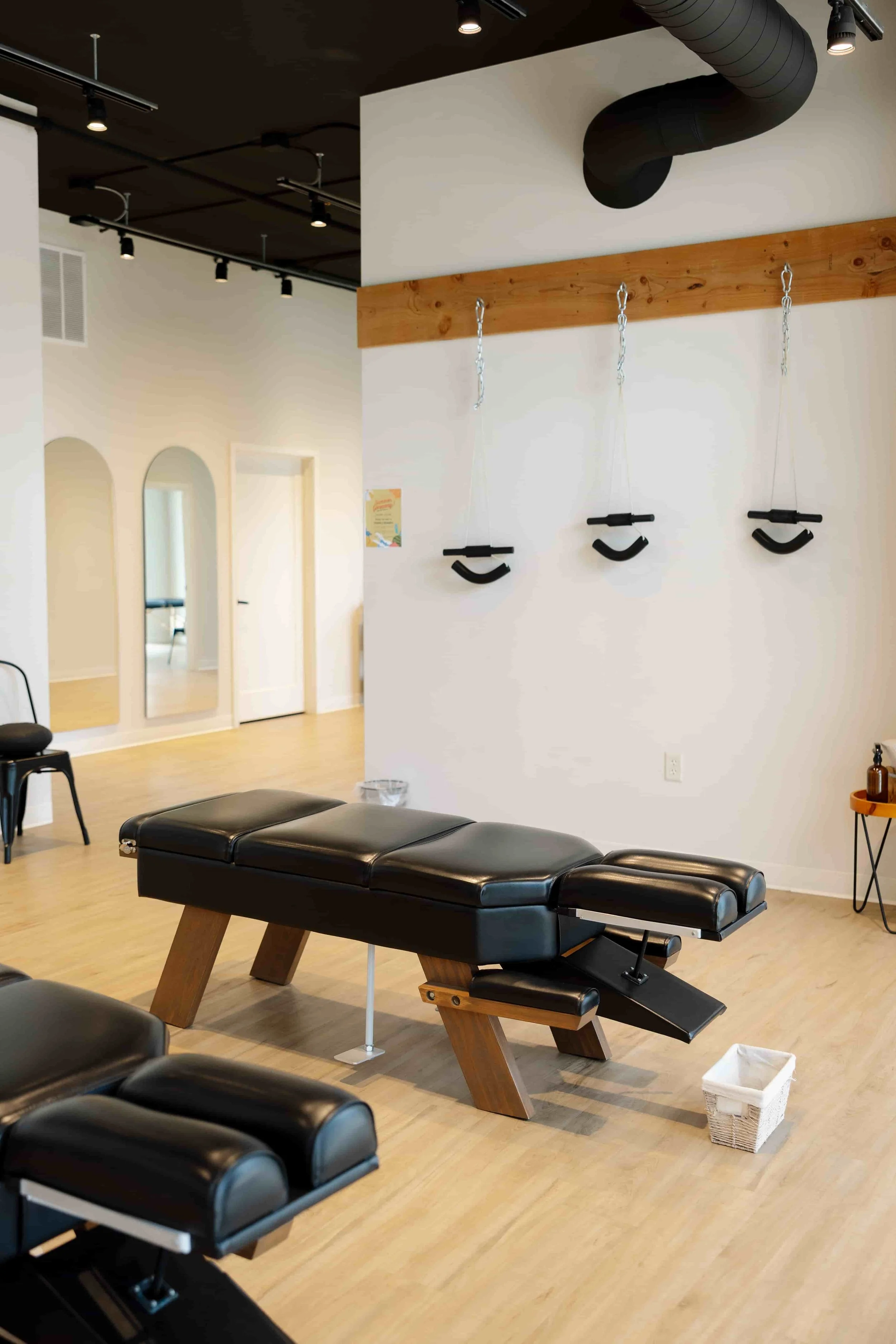A massage therapy room with a massage table, hanging footstools, and a small table.