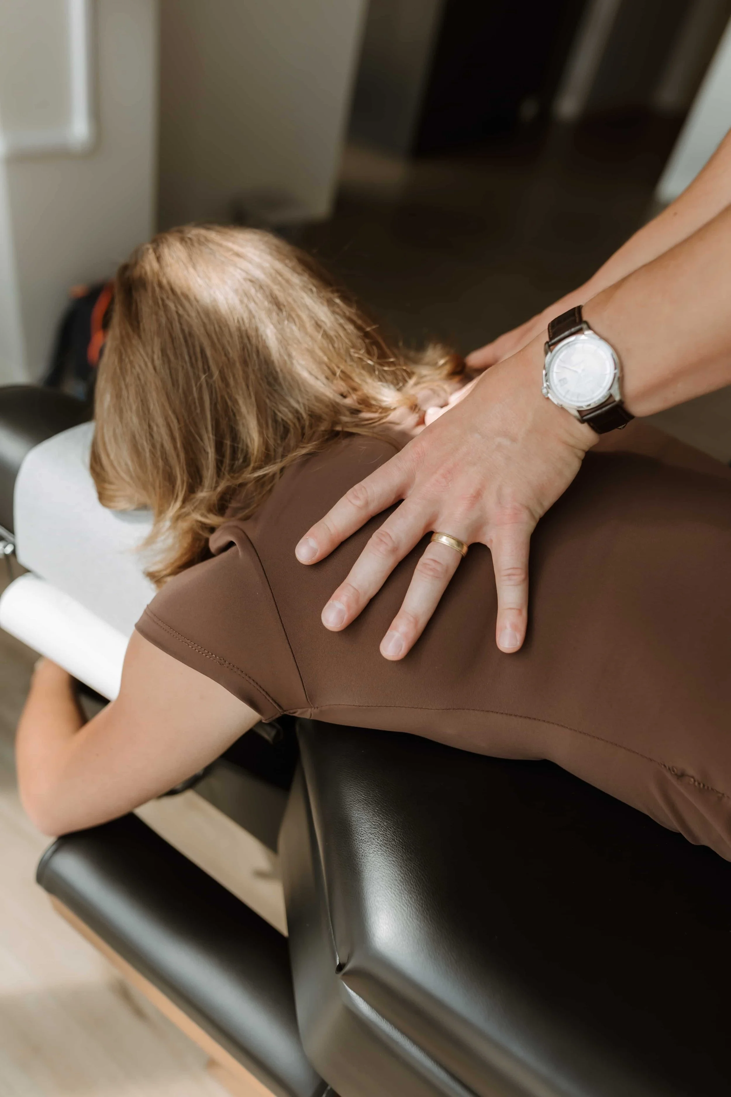 A person receiving a chiropractic adjustment or massage on their upper back from a practitioner.