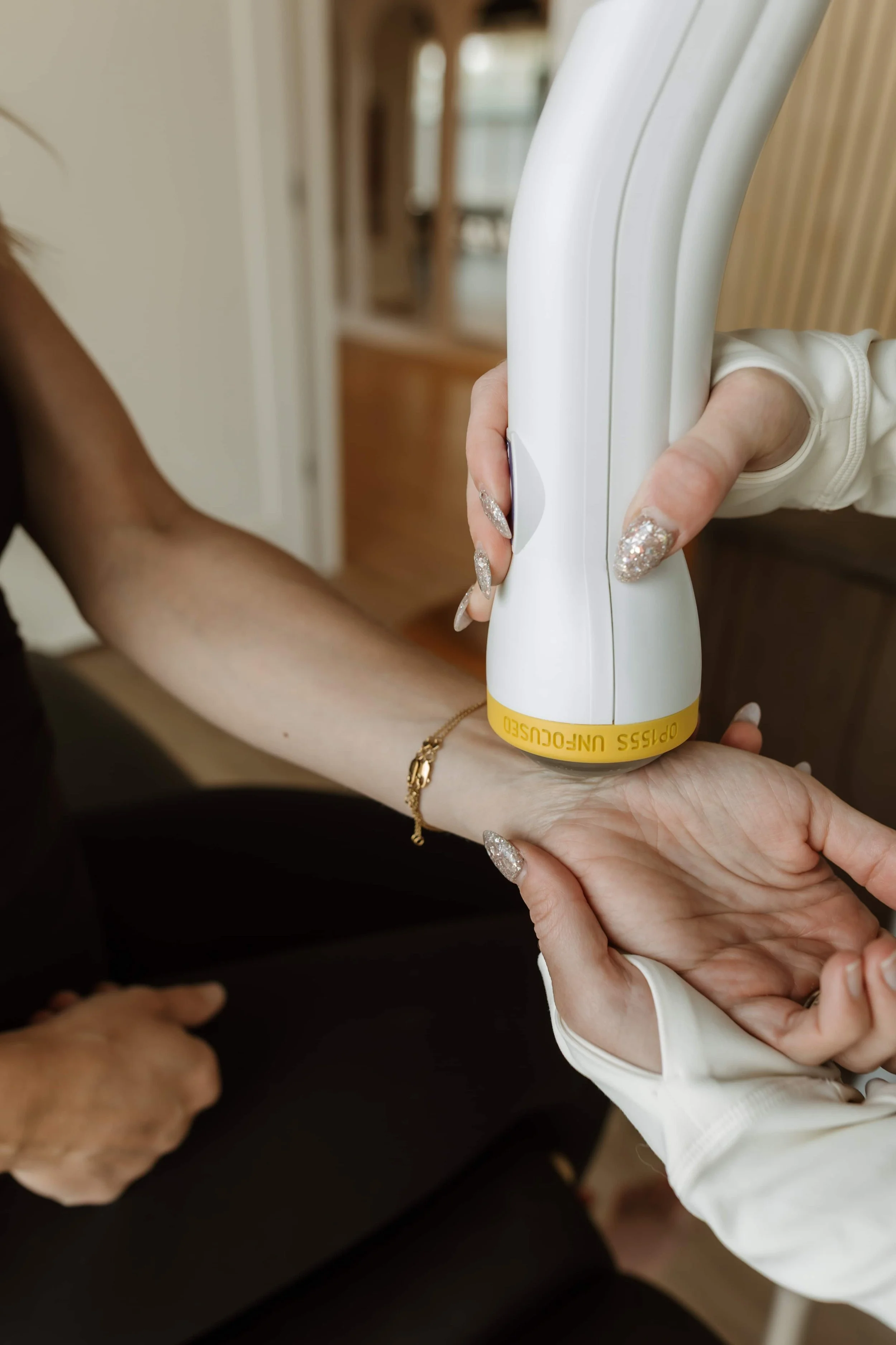 A person receiving a blood oxygen level measurement with a pulse oximeter on their finger, with two people present in a home setting.