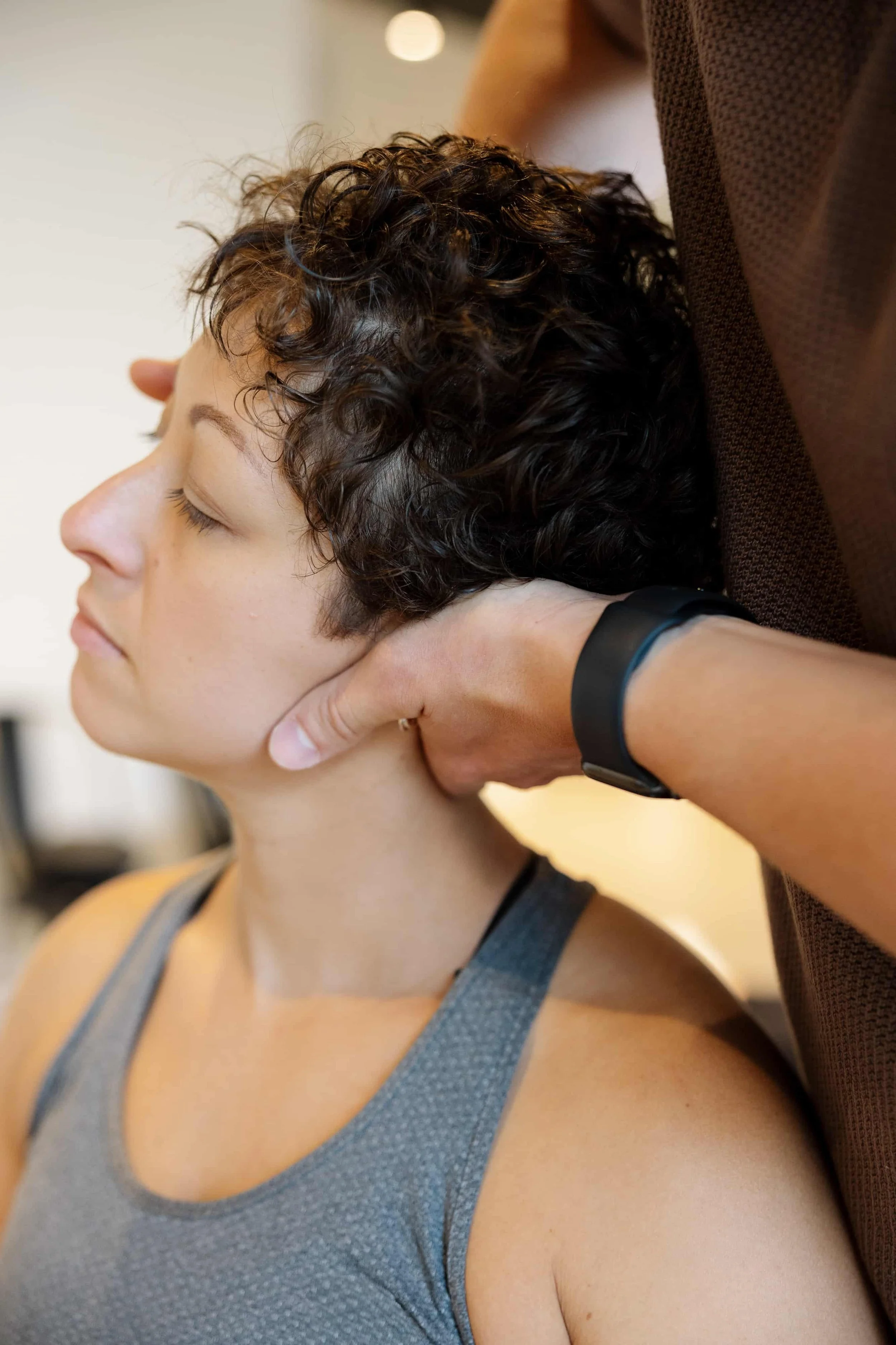 A woman receiving a chiropractic adjustment with her eyes closed, in a relaxed setting.