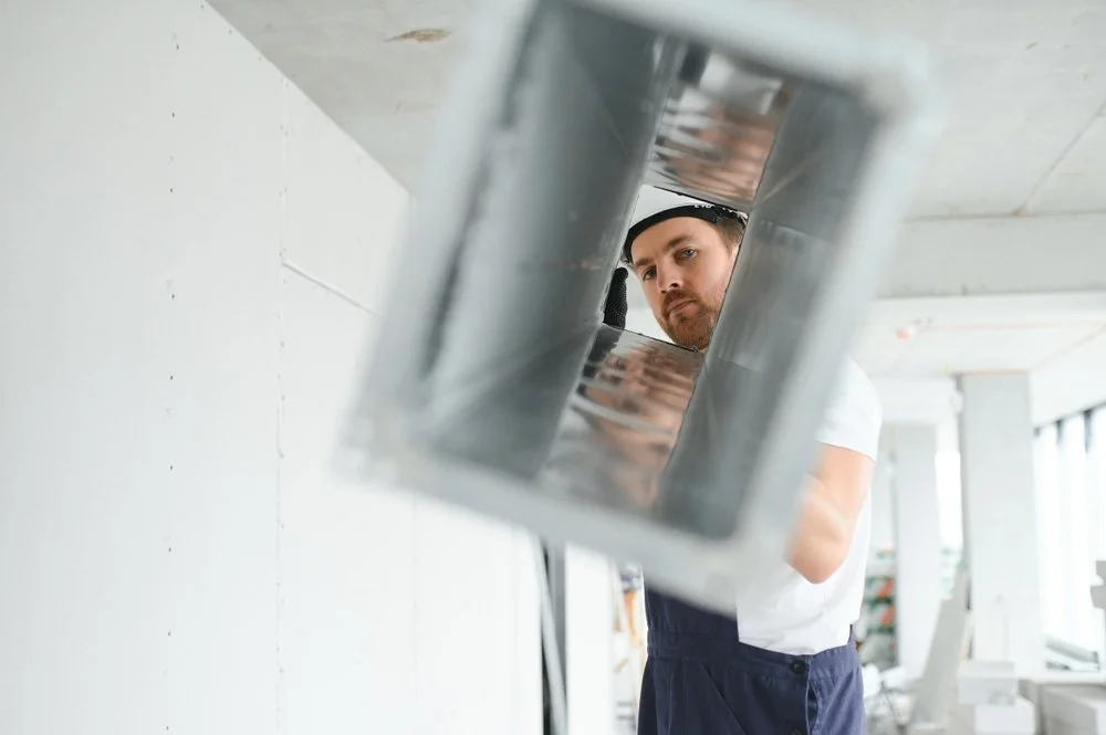 Man inspecting a duct or vent in a building.