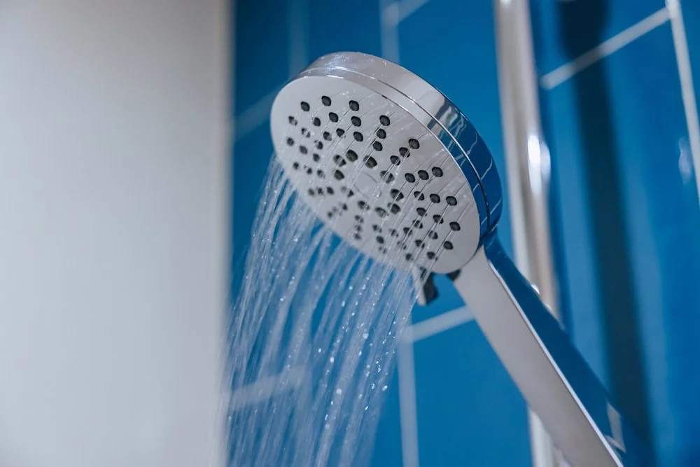Close-up of a handheld showerhead with water flowing.