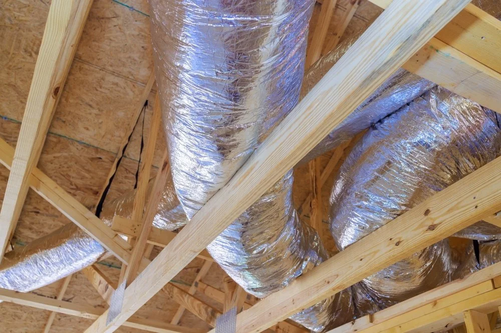 Insulation ducts installed in a building's ceiling framing, covered with reflective silver insulation material.