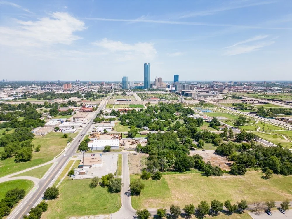 Aerial view of a cityscape with tall buildings, green parks, and roads on a sunny day