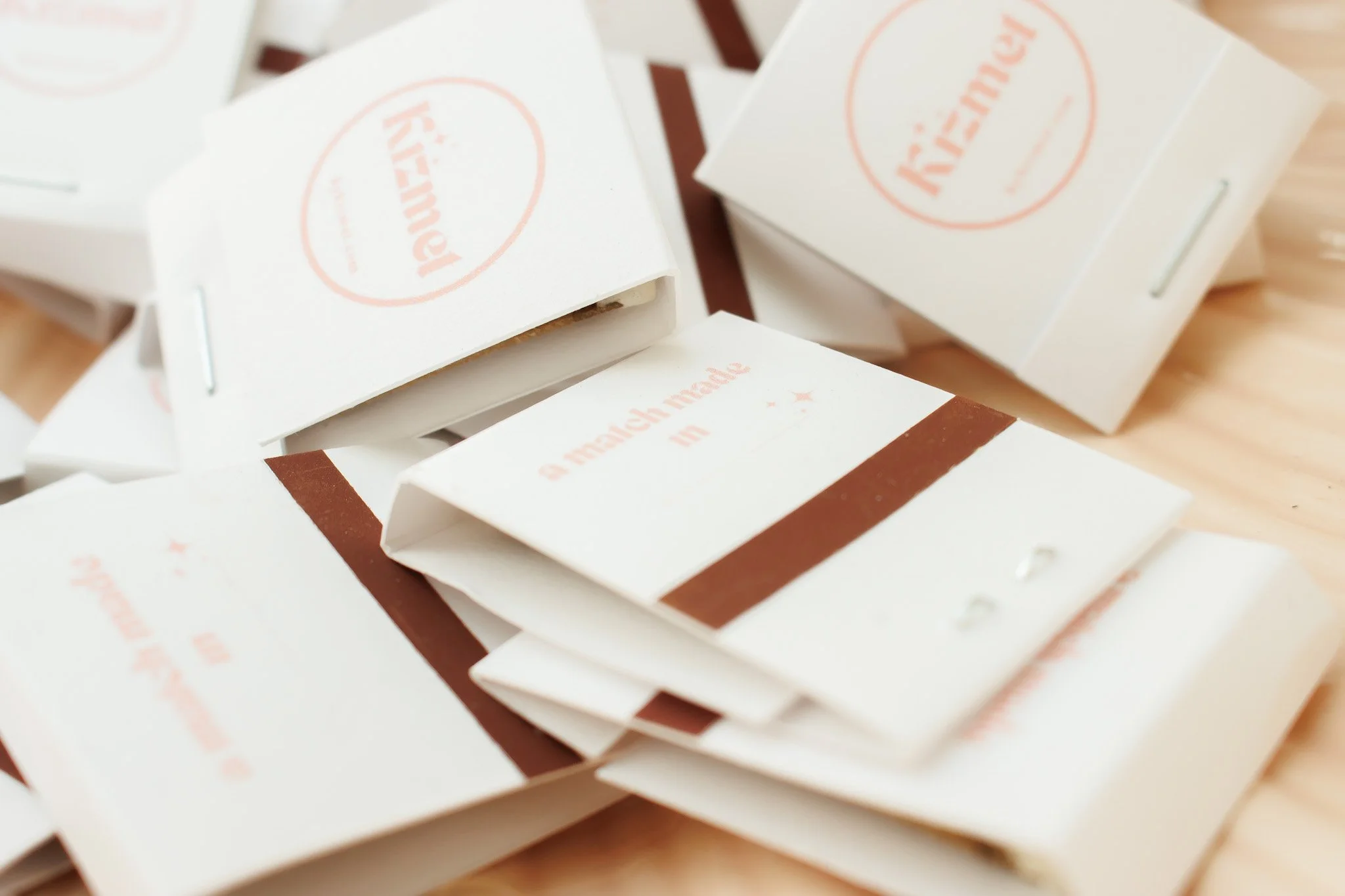 Several small white paper boxes with brown accents and red text, partially opened, rest on a wooden surface.
