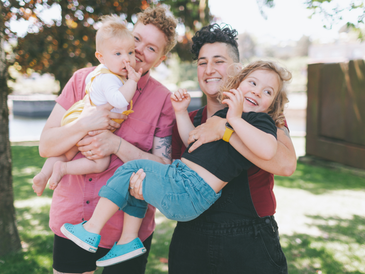 LBGTQ parents with their children embracing with smiles. All parents are welcome at Fresh Therapy LLC.