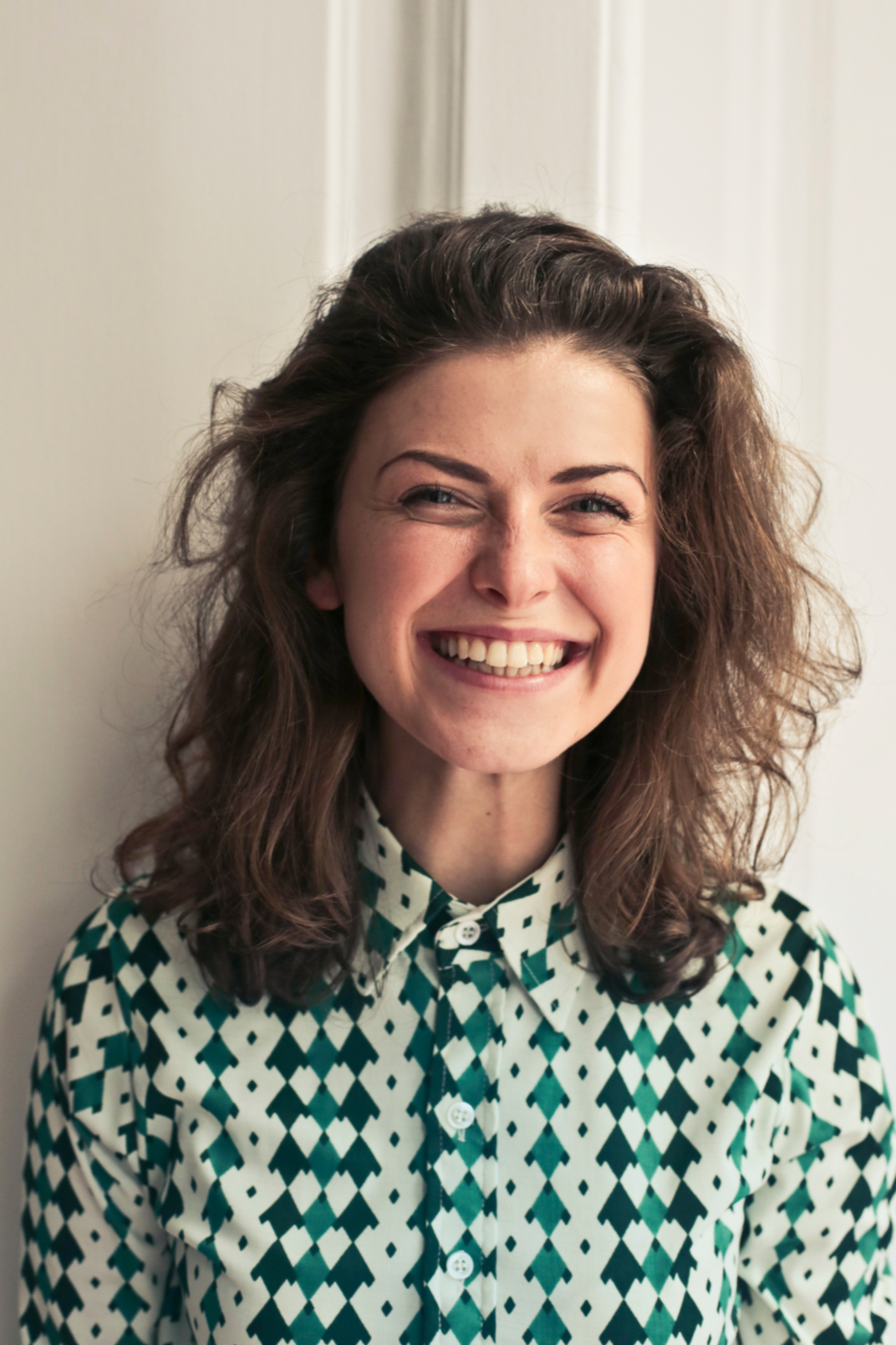 Women with large smile on face and green and white shirt after noticing improvements in ability to relax after attending anxiety therapy with Fresh Therapy LLC.