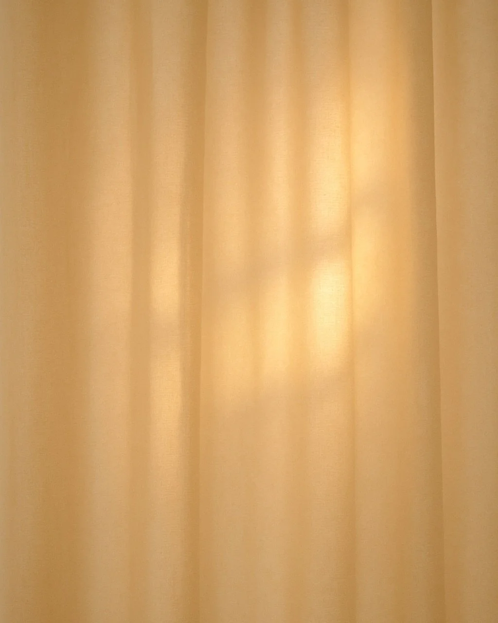 Cream-colored curtains hanging with soft light filtering through.