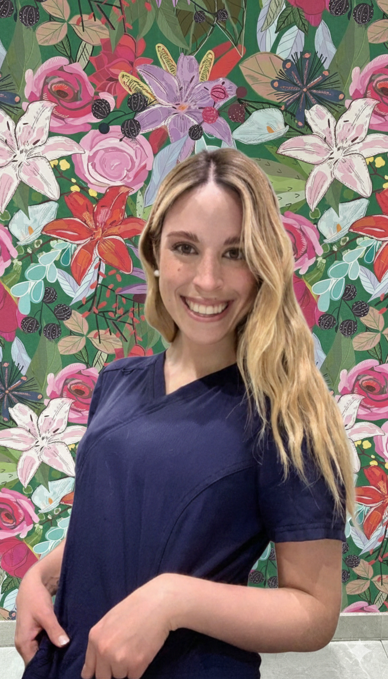 Una mujer sonriendo frente a un fondo con flores coloridas, incluyendo lirios, rosas y otras plantas.