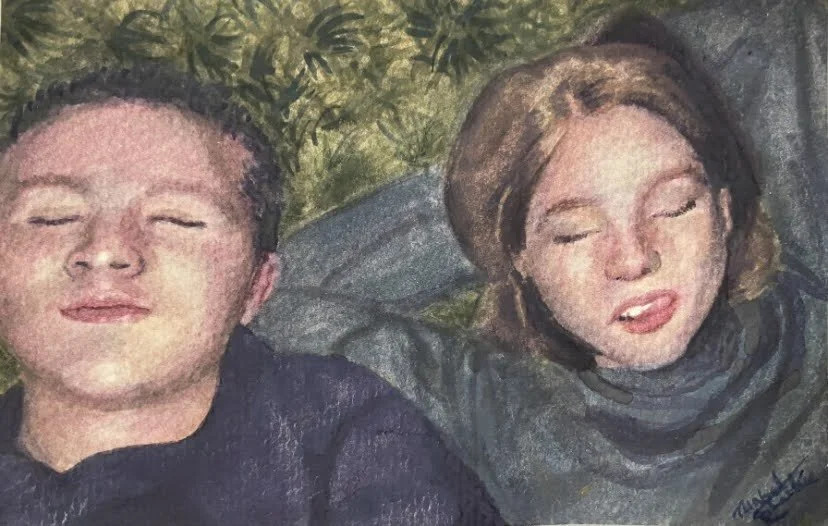 Two people lying on the grass with eyes closed, one with short hair and the other with shoulder-length hair, outdoors in a natural setting.