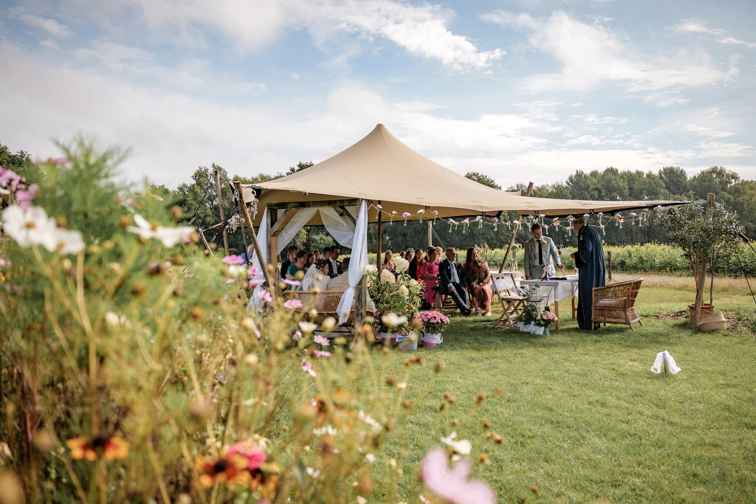 Buiten trouwen in een tuin met een ceremonie onder een grote tent., gefotografeerd door een professionele fotograaf uit regio Gelderland