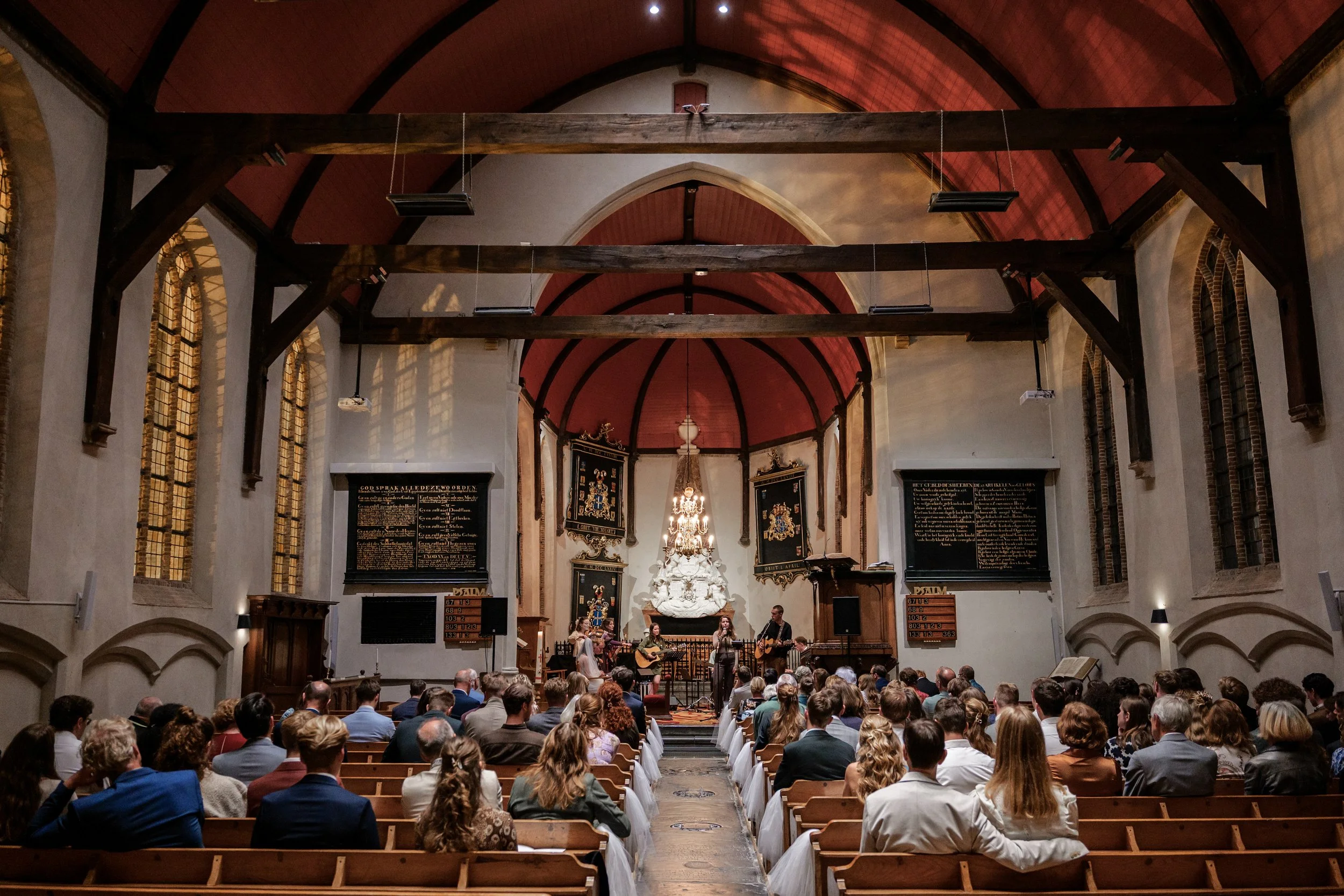 Een kerkzaal met een koor en een muziekgroep die optreedt voor een volle kerk tijdens een trouwdienst. Door Mateo Media gefotografeerd.