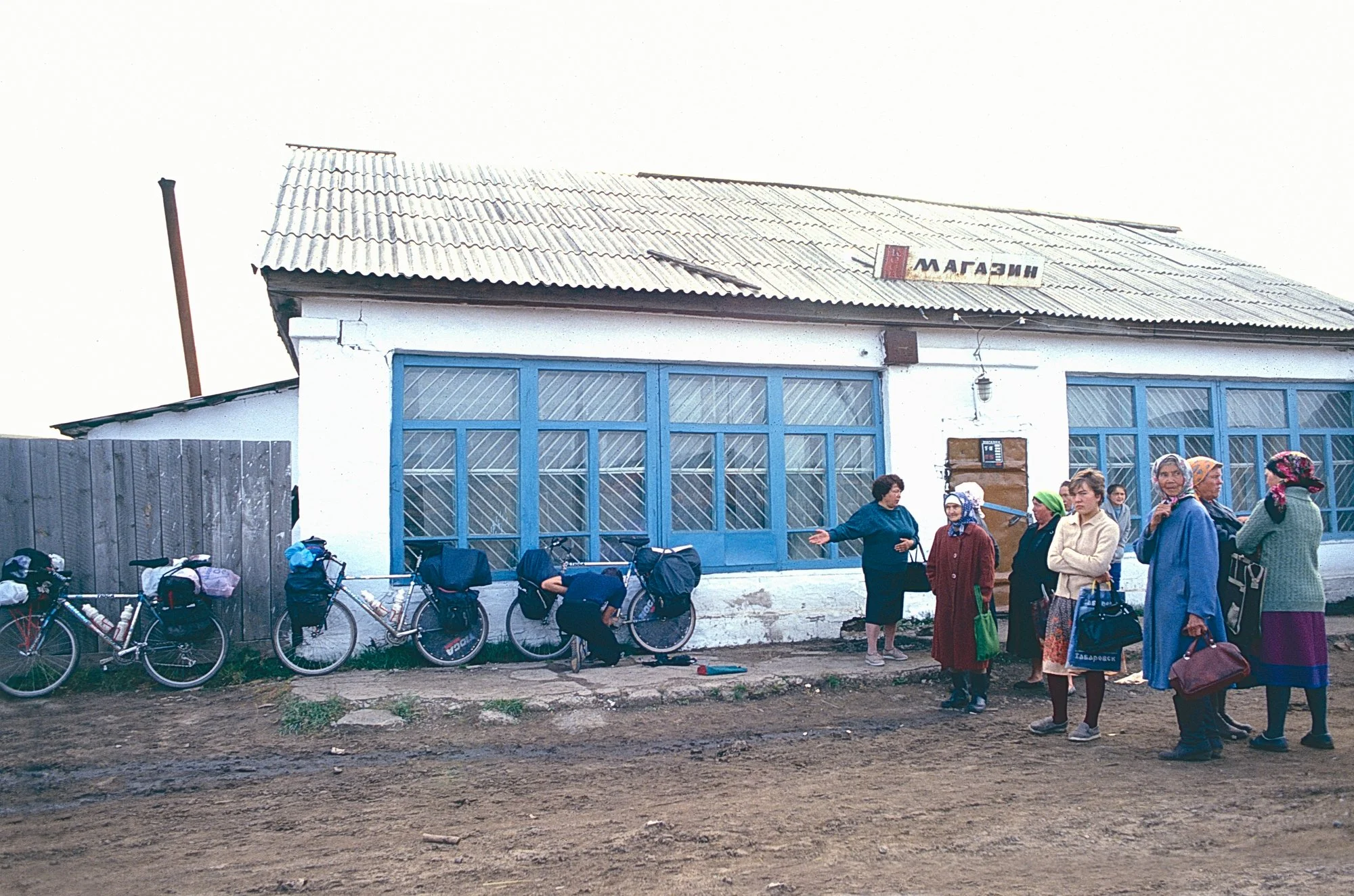 Women discuss the presence of foreigners in bike tights, a downside of Perestroika, as they wait for the general store to open.