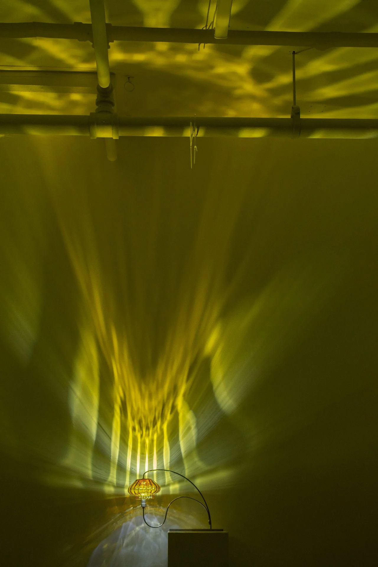Illuminated, wider view of the lamp on a table displays textured yellow and white light.