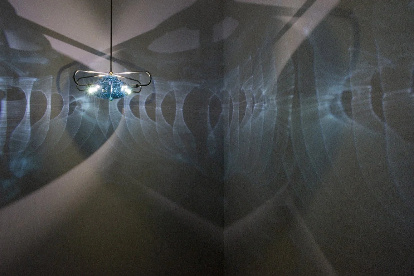 Illuminated, wider view of the fixture displays blue light with repeating circular patterns.