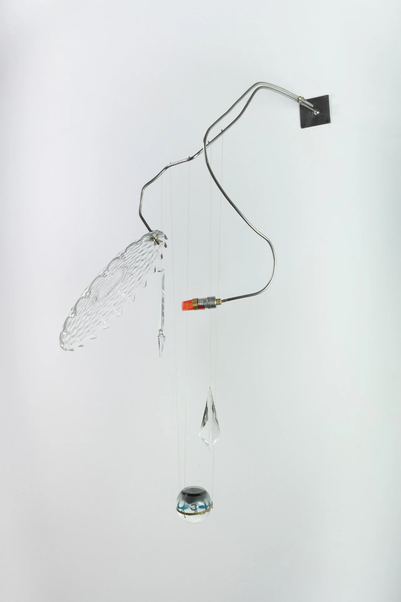 Unilluminated, the clear Fostoria platter with a diamond pattern, two differently shaped chandelier crystals, and a clear/blue spherical paperweight are emphasized.