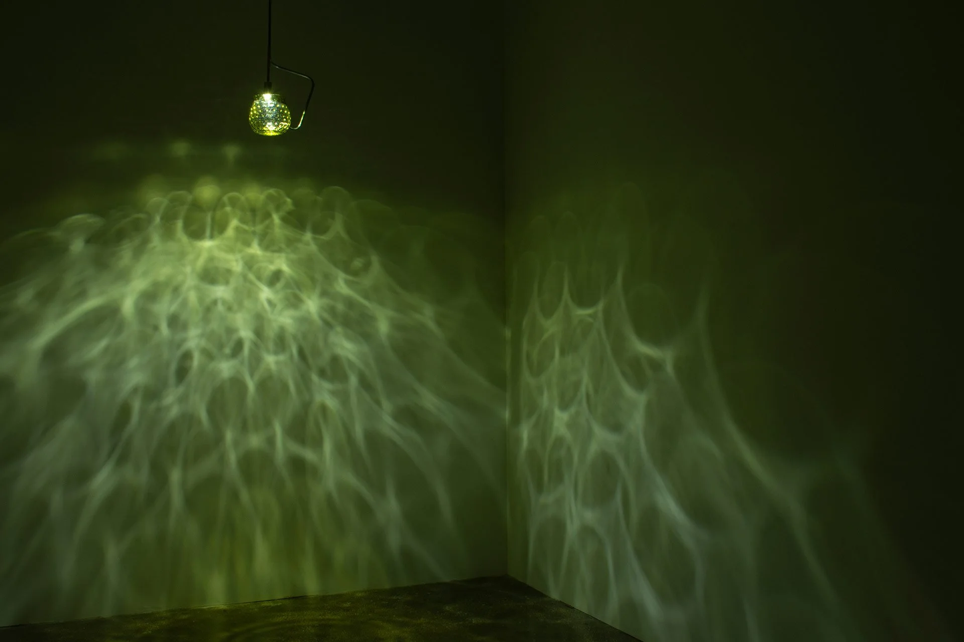 Illuminated, wider view of the fixture displays green, water-like light.