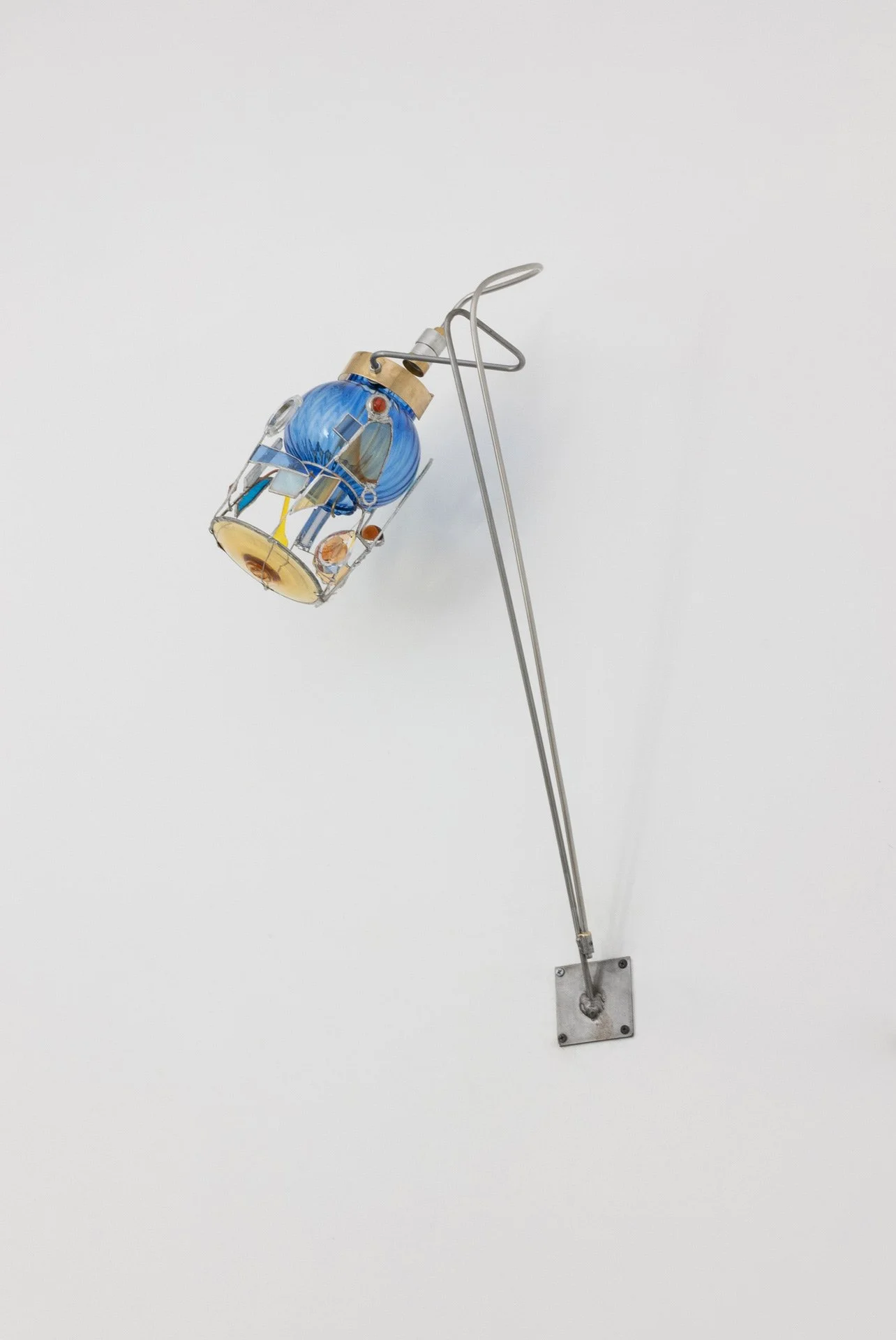 Unilluminated, the blue ribbed lampshade and multicolor collaged details are emphasized.