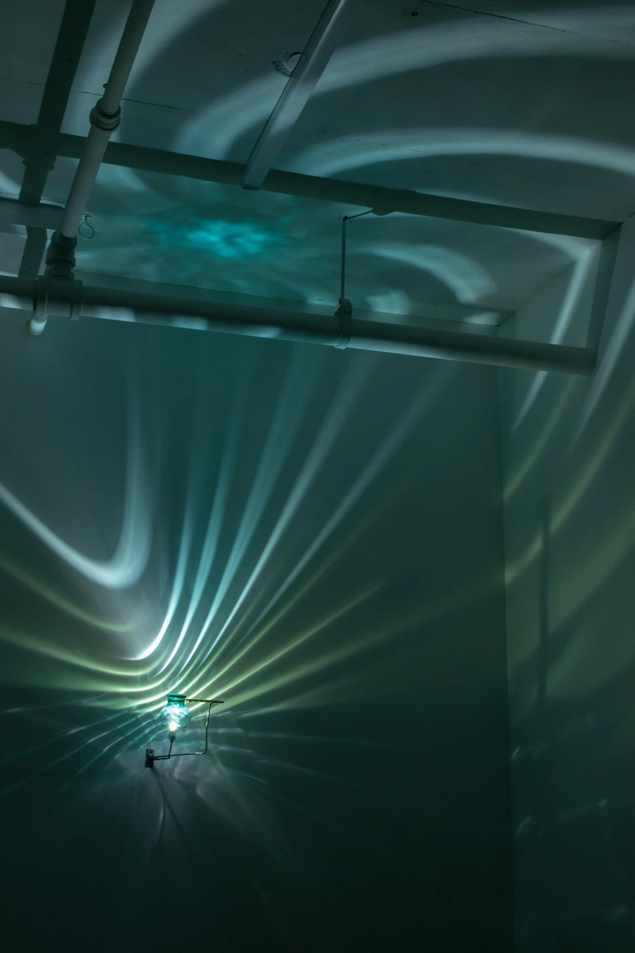 Illuminated, wider view of the fixture displays swirled blue and green light.