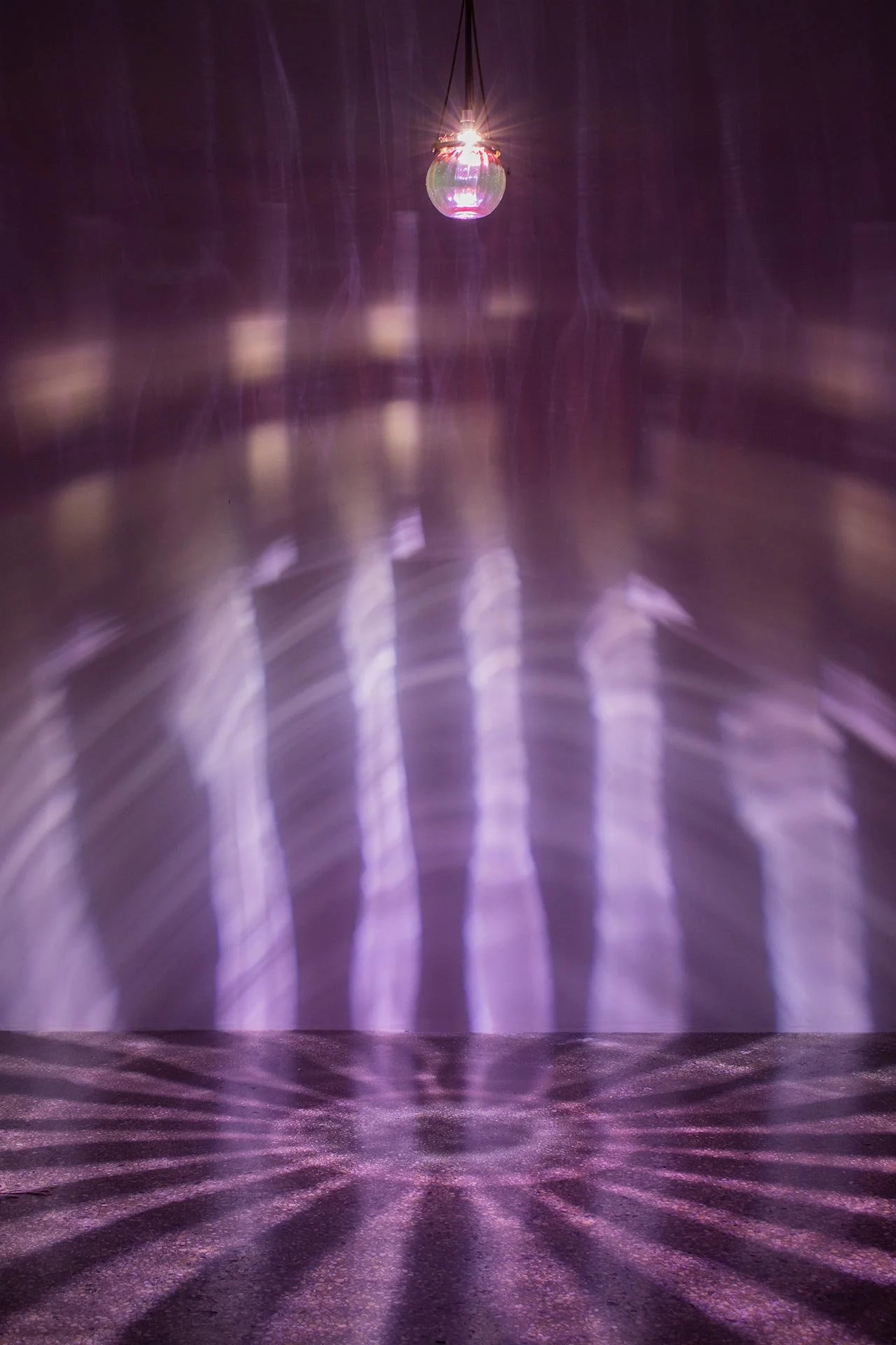 Illuminated, wider view of the fixture displays vertical lines of pink light.