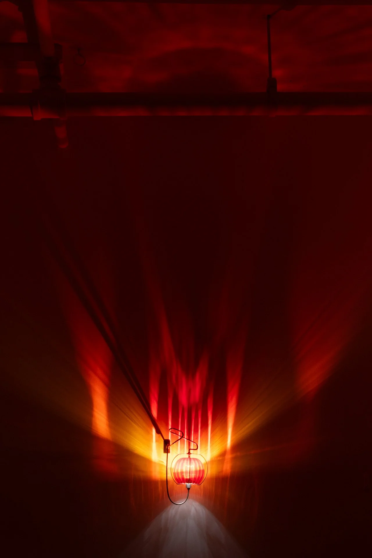 Illuminated, wider view of the fixture displays red and orange light that splits linearly.