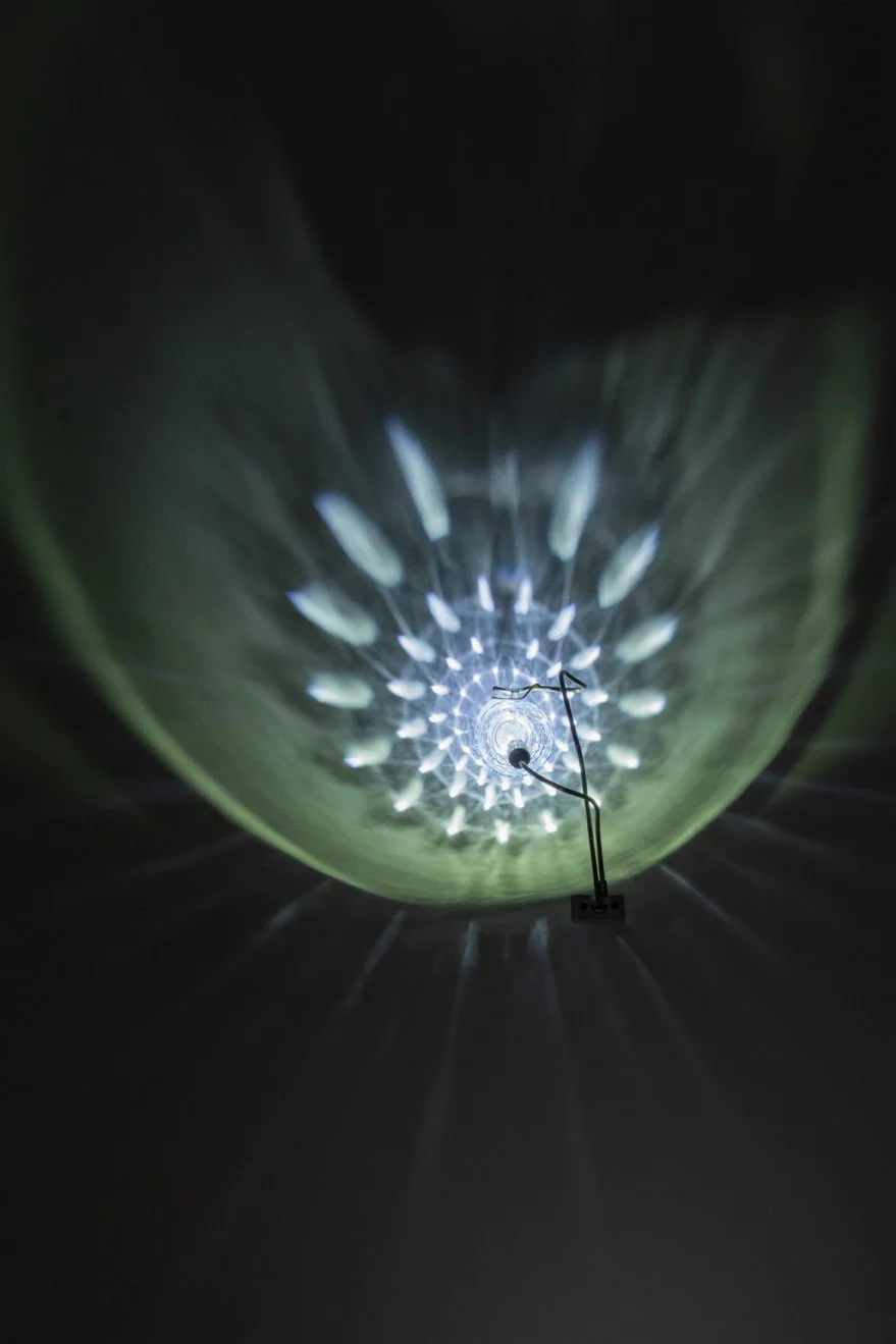 Illuminated, wider view of the fixture displays white light in a mandala-like pattern.