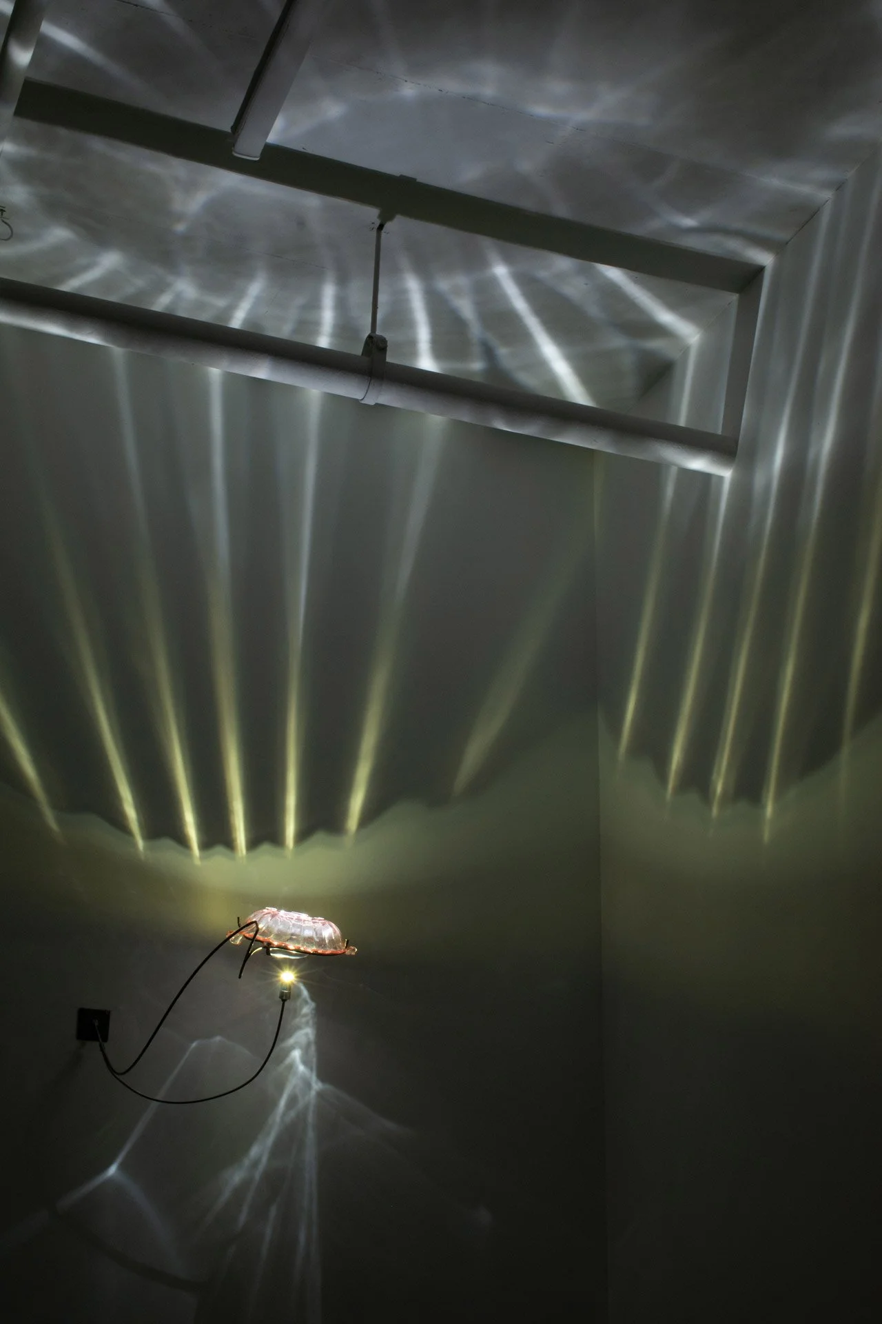 Illuminated, a wider view of the fixture displays white light with yellow streaks emanating from it, resembling light streaming through a cloud or lightning.