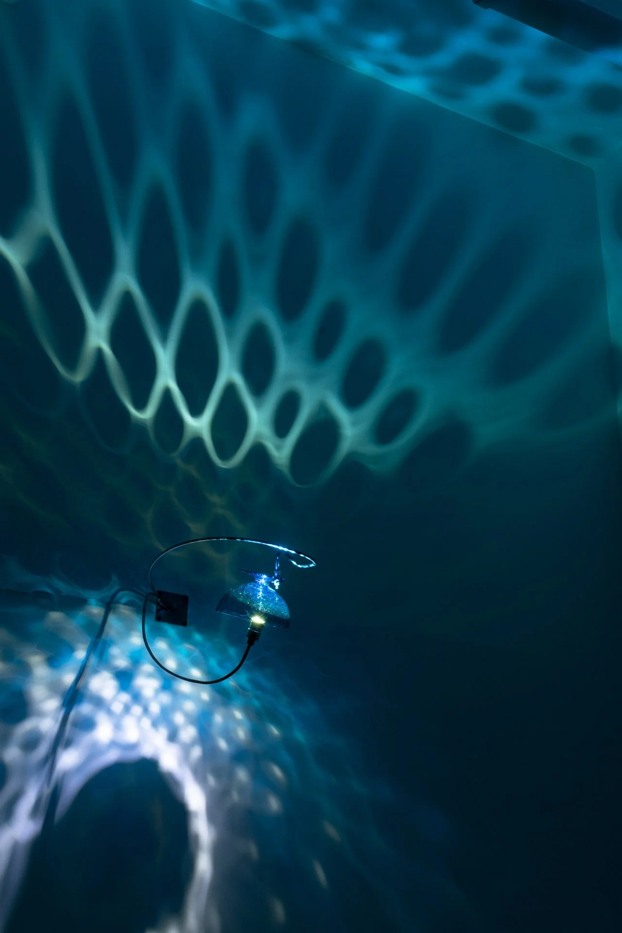 Illuminated, wider view of the fixture displays blue light with a water-like pattern.