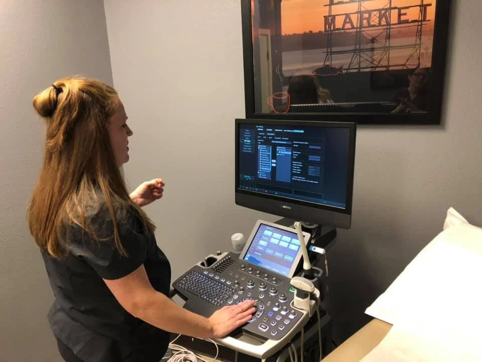Medical professional operating ultrasound equipment in a hospital room.