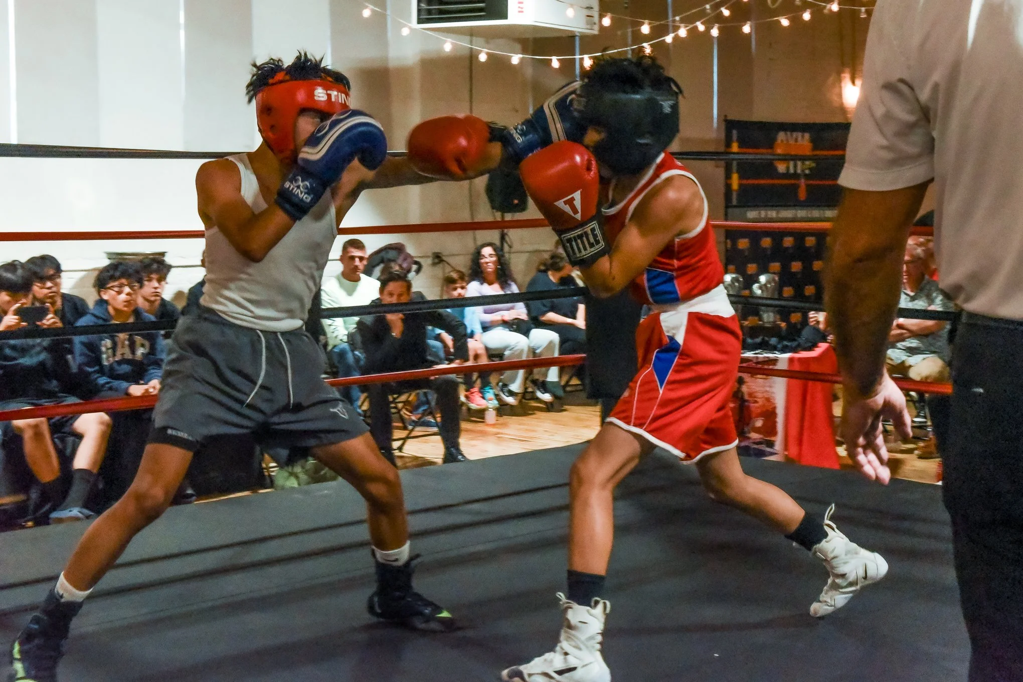 Amateur boxers sparring in ring with crowd watching at Gleason's New Jersey boxing event