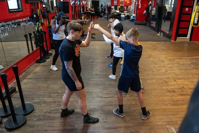 Young boxers practicing technique with trainer at Gleason's youth boxing program