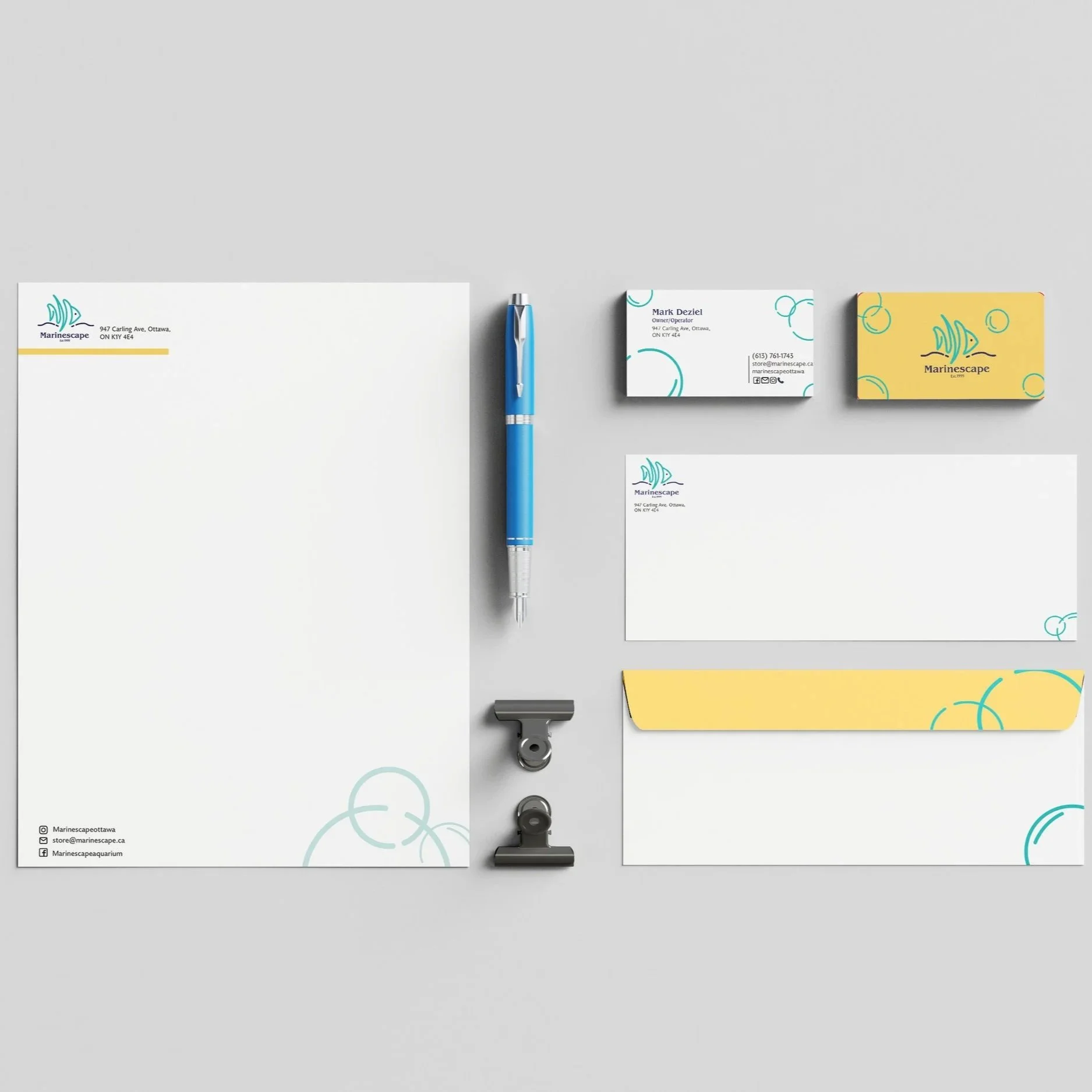 Stationery set including letterhead, business card, envelopes, and additional cards with marine-themed logo and design in blue and yellow colors on a gray background.