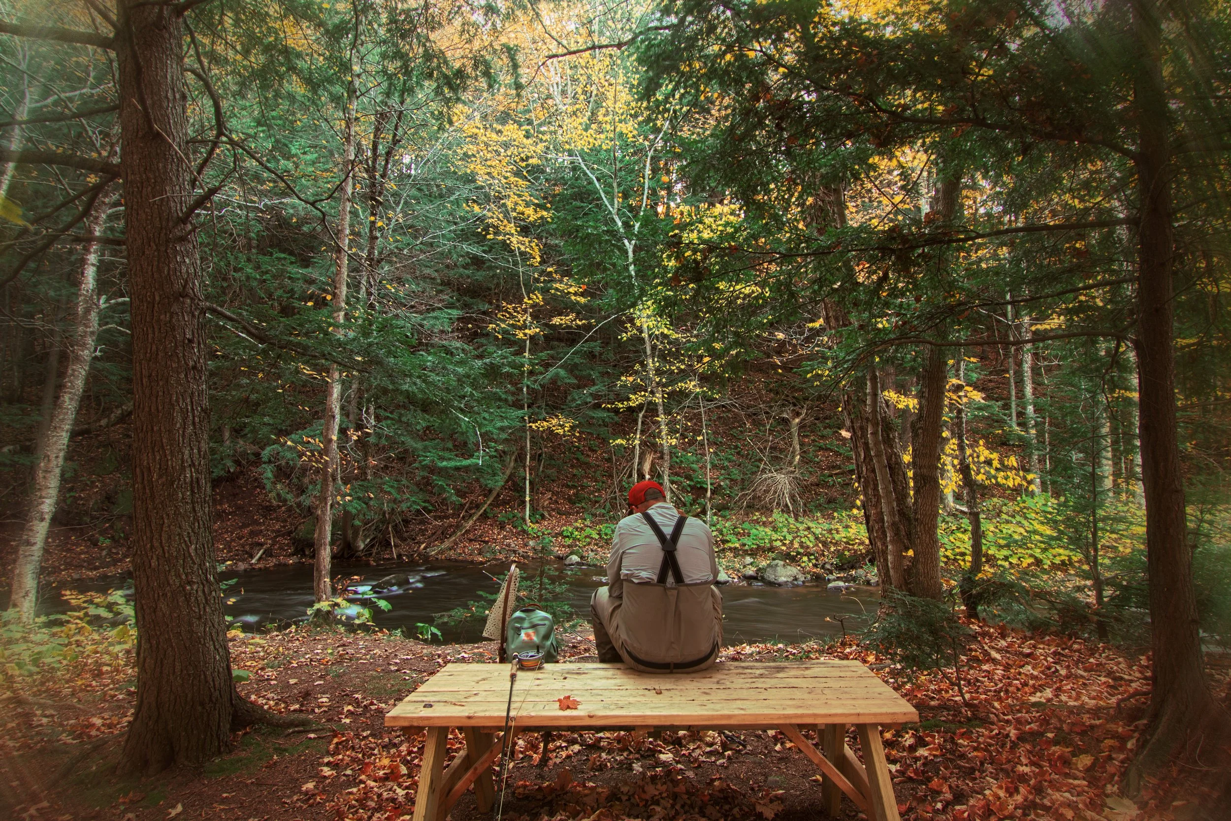 Man sitting on picnic table fishing Rippling River Resort