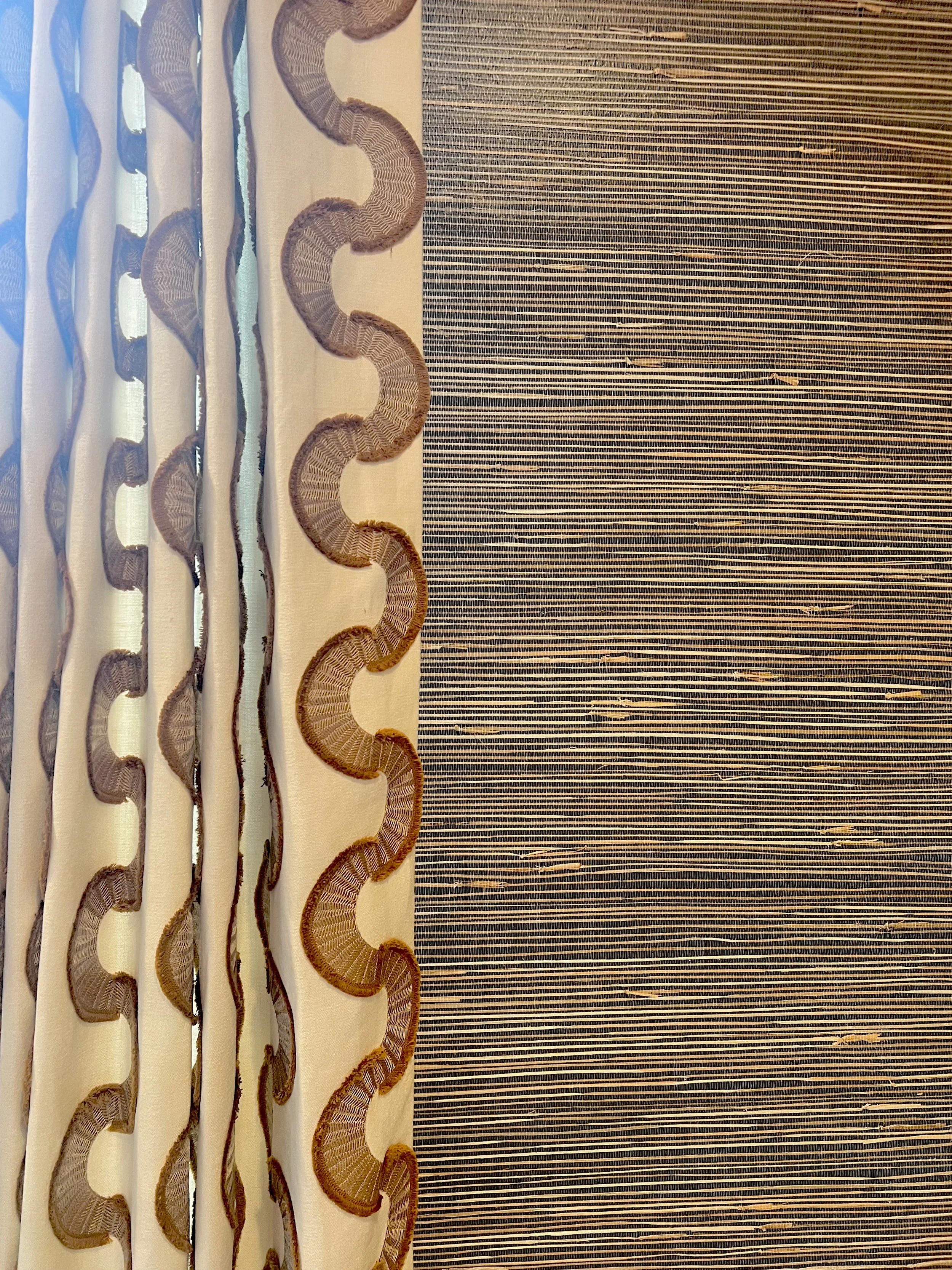 Close-up of a curtain with decorative embroidery and a striped fabric background.