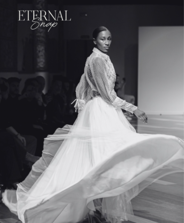 Mujer desfilando en la pasarela usando vestido de novia de tul y encaje en un evento de moda llamado ETERNAL Snap.