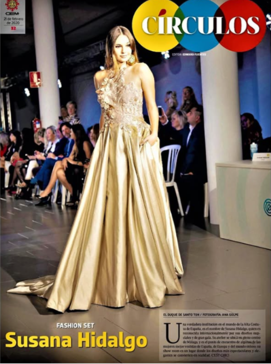 Modelo en pasarela con vestido dorado en evento de moda, audiencia y periodistas en el fondo, cartel de revista Círculos, texto con nombre Susana Hidalgo y descripción del evento de moda.
