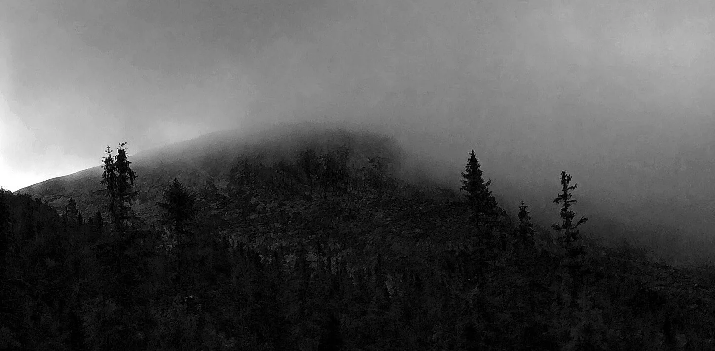 Black and white image of a mountain with a misty bakground